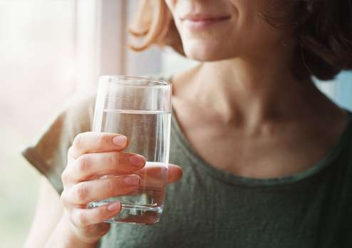 Woman drinking a glass of Sidra Water at home